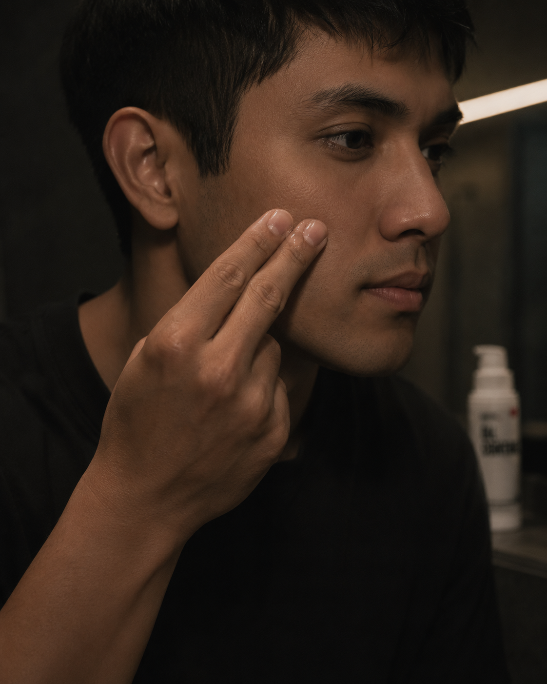 Man tapping serum onto his cheek with two fingers
