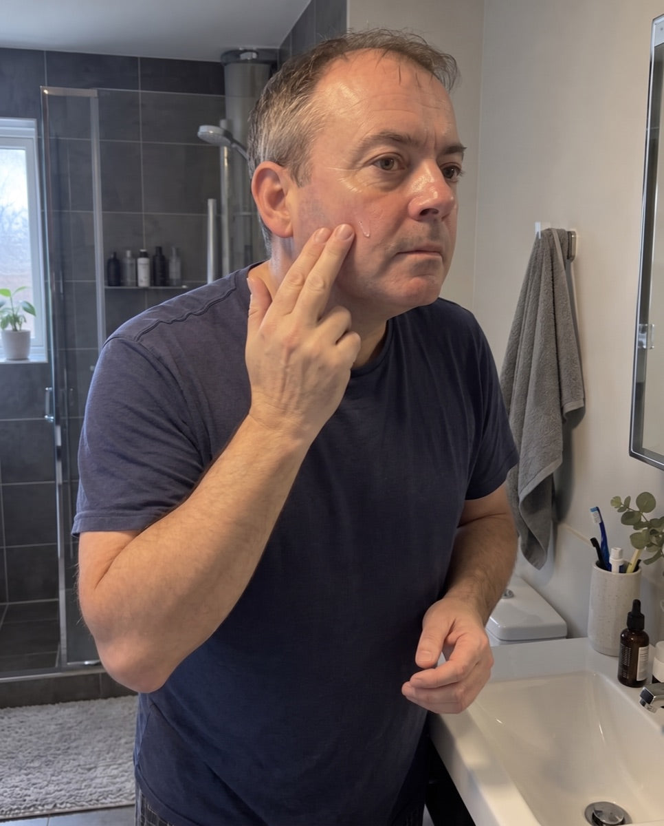 Man in his fifties gently applying serum to his cheek